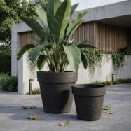 Black jumbo stone textured planters in a modern courtyard